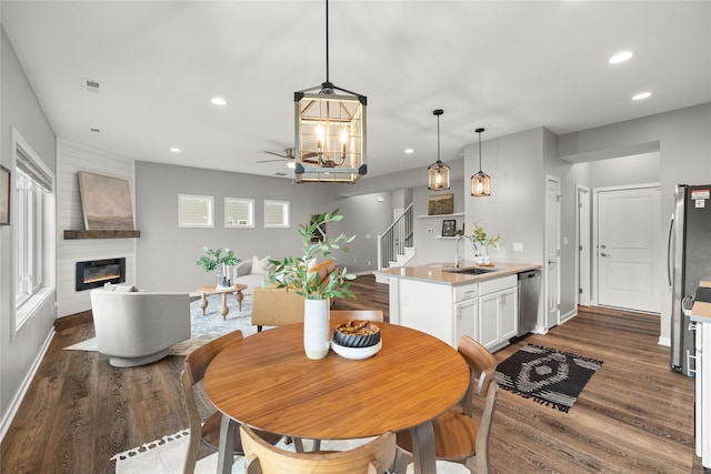 832 Kinney Cir NE, Bondurant, IA 50035 - dining room with dark wood-style floors, recessed lighting, a large fireplace, stairs, and a chandelier