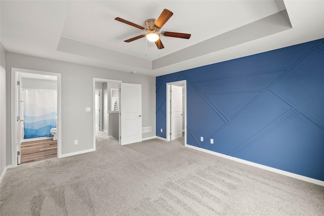 832 Kinney Cir NE, Bondurant, IA 50035 - unfurnished bedroom with a tray ceiling, carpet flooring, connected bathroom, and a ceiling fan