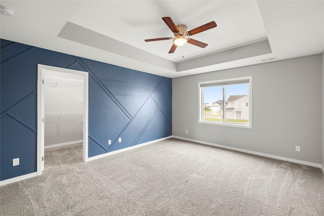 832 Kinney Cir NE, Bondurant, IA 50035 - empty room featuring a tray ceiling, a ceiling fan, carpet floors, and a decorative wall