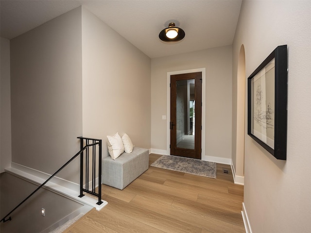 1128 NW 29th Ct, Grimes, IA 50111 - corridor with light wood-style flooring, arched walkways, and an upstairs landing