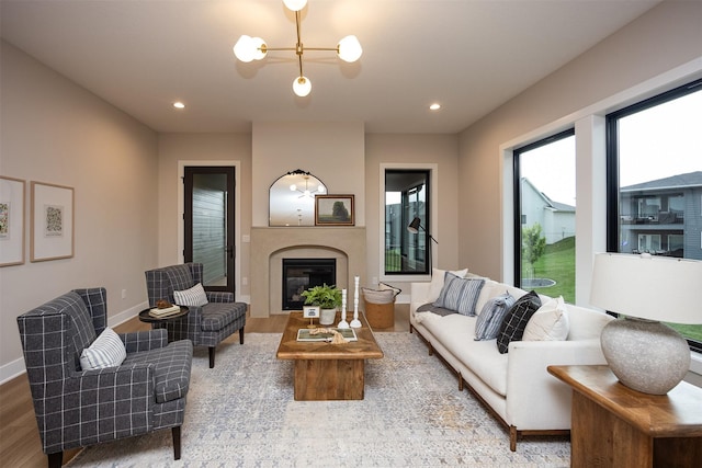 1128 NW 29th Ct, Grimes, IA 50111 - living room featuring wood finished floors, a glass covered fireplace, recessed lighting, and a chandelier