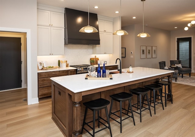 1128 NW 29th Ct, Grimes, IA 50111 - kitchen with range hood, light wood-style floors, stainless steel gas range, white cabinets, and recessed lighting
