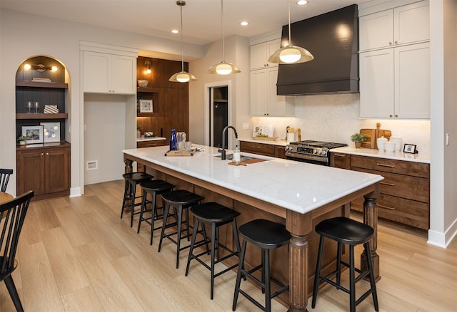 1128 NW 29th Ct, Grimes, IA 50111 - kitchen featuring wall chimney exhaust hood, gas stove, light wood-style floors, white cabinetry, and recessed lighting
