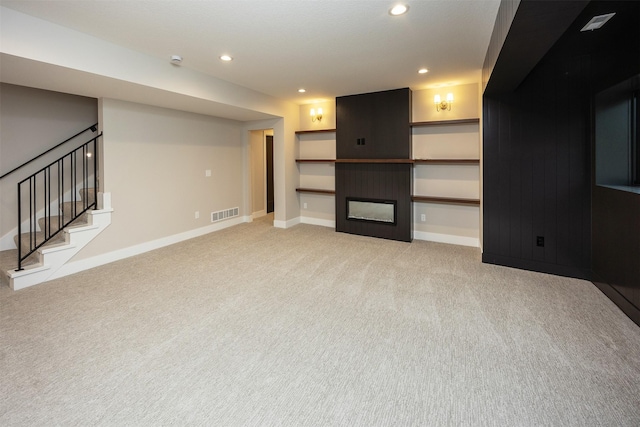 1128 NW 29th Ct, Grimes, IA 50111 - unfurnished living room with light colored carpet, stairway, recessed lighting, and a glass covered fireplace