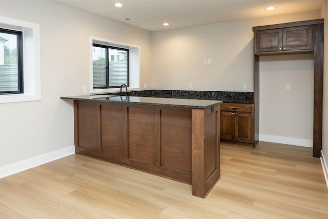 1128 NW 29th Ct, Grimes, IA 50111 - kitchen with light wood finished floors, dark stone counters, recessed lighting, a peninsula, and dark brown cabinetry