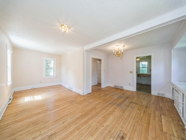 2928 34th St, Des Moines, IA 50310 - spare room with a chandelier, light wood-type flooring, and a textured ceiling
