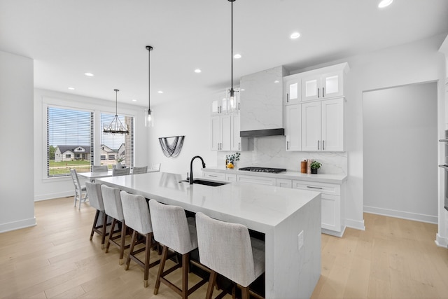 1305 NW 28th St, Grimes, IA 50111 - kitchen featuring stainless steel gas stovetop, backsplash, an island with sink, light wood-type flooring, and recessed lighting