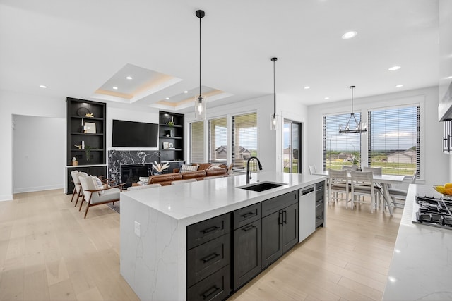 1305 NW 28th St, Grimes, IA 50111 - kitchen with stainless steel appliances, a high end fireplace, light wood-style floors, a kitchen island with sink, and light stone counters