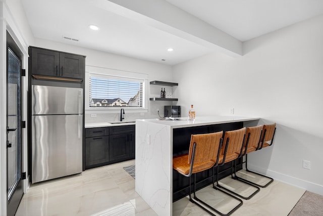 1305 NW 28th St, Grimes, IA 50111 - kitchen featuring freestanding refrigerator, a breakfast bar area, a peninsula, recessed lighting, and dark cabinets