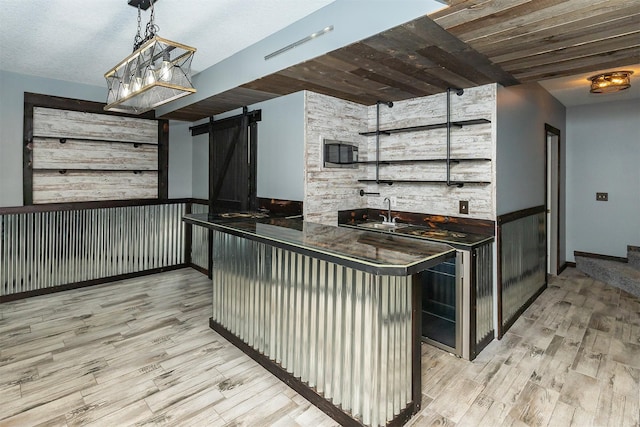 3170 E Kenyon Ave, Des Moines, IA 50320 - kitchen with a barn door, light wood finished floors, dark countertops, and decorative light fixtures
