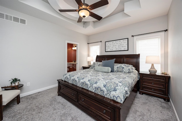 9824 Dunmore Cir, Johnston, IA 50131 - bedroom with light carpet, a tray ceiling, ceiling fan, and connected bathroom