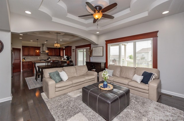 9824 Dunmore Cir, Johnston, IA 50131 - living area featuring ceiling fan, dark wood-style floors, a tray ceiling, arched walkways, and recessed lighting