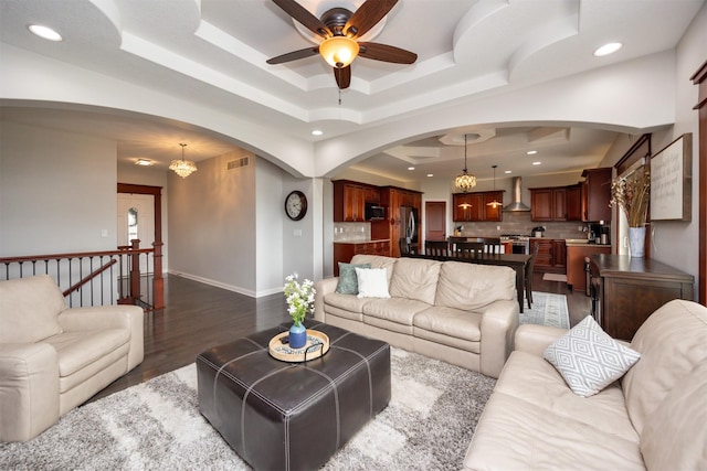 9824 Dunmore Cir, Johnston, IA 50131 - living room with arched walkways, a ceiling fan, a tray ceiling, dark wood-style flooring, and recessed lighting