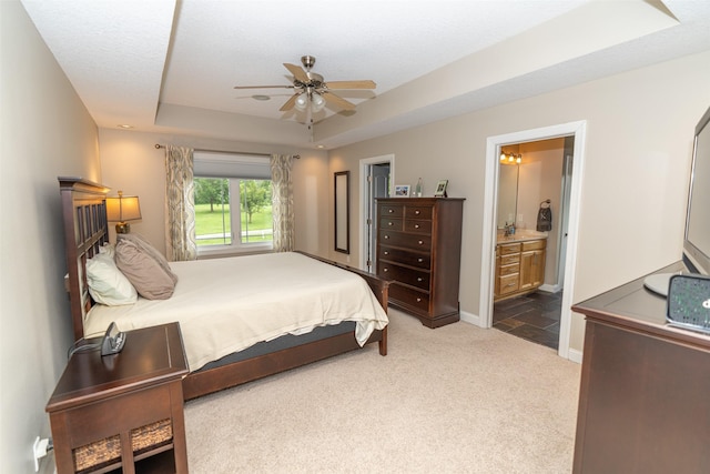 2726 SE 11th St, West Des Moines, IA 50265 - carpeted bedroom featuring a tray ceiling, a ceiling fan, and ensuite bath