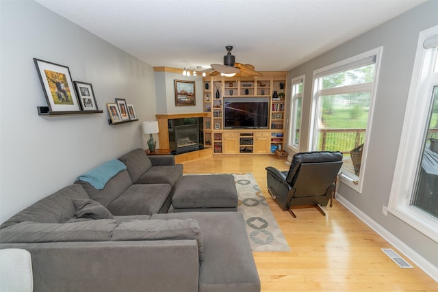 2726 SE 11th St, West Des Moines, IA 50265 - living area featuring a ceiling fan, light wood-type flooring, a glass covered fireplace, and built in shelves