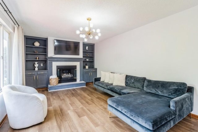 4965 Raintree Dr, West Des Moines, IA 50265 - living area featuring light wood-style floors, a chandelier, a glass covered fireplace, and built in features