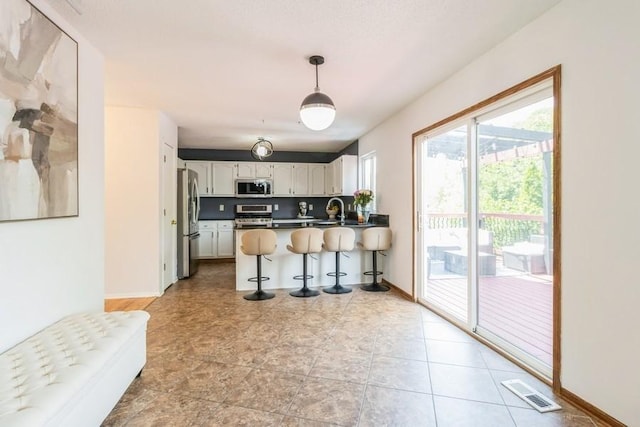 4965 Raintree Dr, West Des Moines, IA 50265 - kitchen featuring stainless steel appliances, a peninsula, a breakfast bar, pendant lighting, and white cabinets