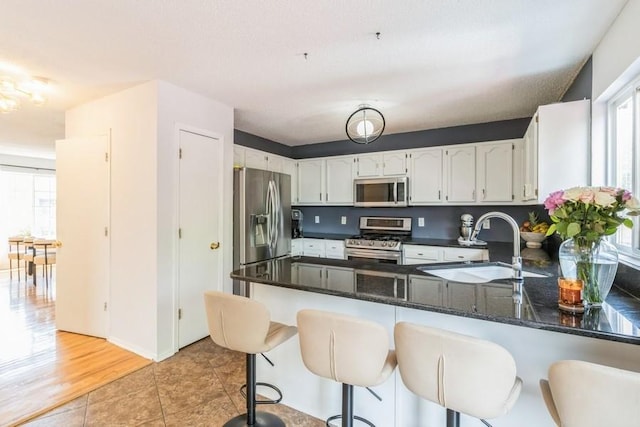 4965 Raintree Dr, West Des Moines, IA 50265 - kitchen featuring stainless steel appliances, a peninsula, white cabinetry, light tile patterned flooring, and a breakfast bar area