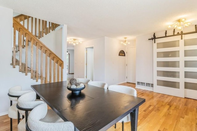 4965 Raintree Dr, West Des Moines, IA 50265 - dining space featuring a barn door, a chandelier, light wood finished floors, and stairway