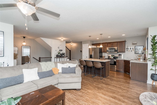 2714 NW Lois Ln, Ankeny, IA 50023 - living room featuring light wood-style flooring, a ceiling fan, stairway, and recessed lighting