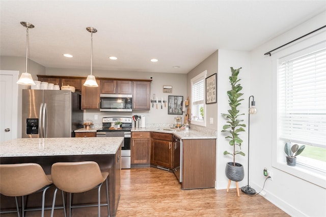 2714 NW Lois Ln, Ankeny, IA 50023 - kitchen with appliances with stainless steel finishes, light wood finished floors, hanging light fixtures, light stone counters, and recessed lighting