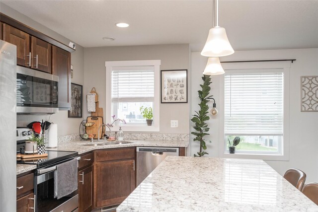 2714 NW Lois Ln, Ankeny, IA 50023 - kitchen with appliances with stainless steel finishes, healthy amount of natural light, dark brown cabinets, light stone counters, and recessed lighting