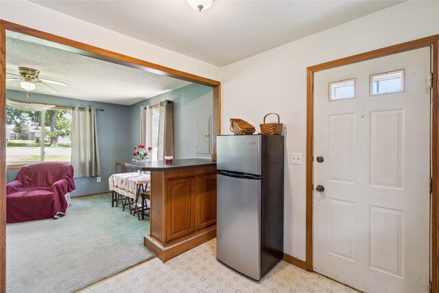 4935 NE 39th Ave, Des Moines, IA 50317 - kitchen with freestanding refrigerator, open floor plan, light floors, brown cabinetry, and dark countertops