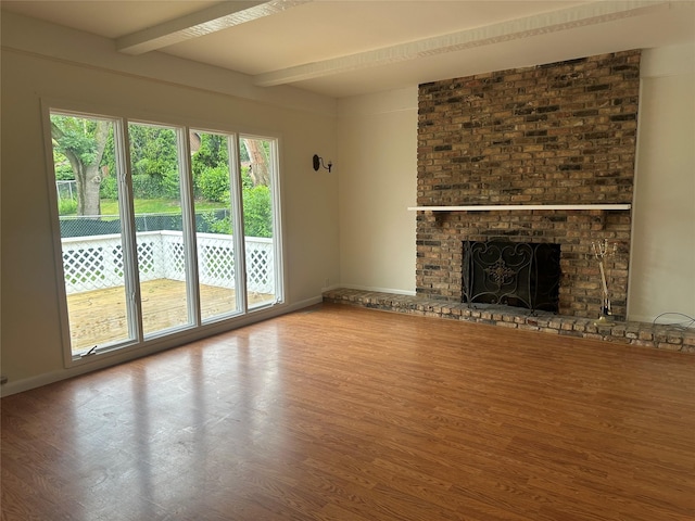 1205 S 4th St, Marshalltown, IA 50158 - unfurnished living room featuring wood finished floors, beam ceiling, and a fireplace