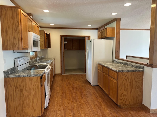 1205 S 4th St, Marshalltown, IA 50158 - kitchen with white appliances, wood finished floors, dark countertops, recessed lighting, and brown cabinetry