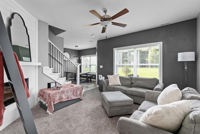 2817 NW Lois Ln, Ankeny, IA 50023 - living room with a fireplace, ceiling fan, stairs, and carpet