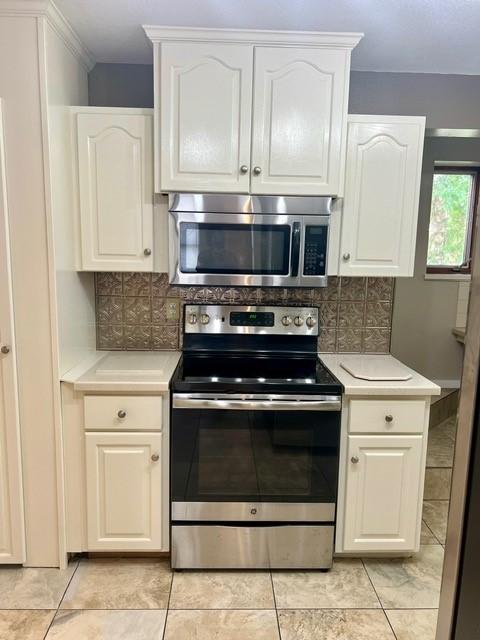 1506 Main St, Adel, IA 50003 - kitchen with stainless steel appliances, light countertops, decorative backsplash, and white cabinets
