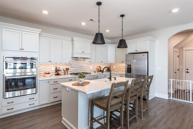 2930 Green Hills Dr, Ames, IA 50014 - kitchen with appliances with stainless steel finishes, arched walkways, light countertops, dark wood-style floors, and backsplash
