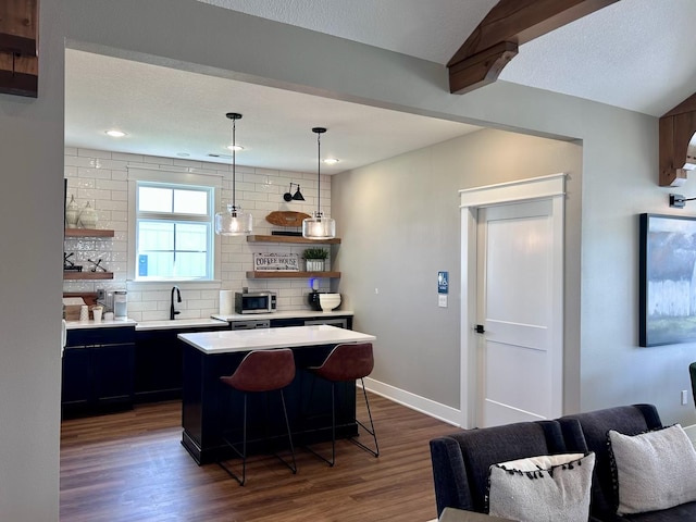 2930 Green Hills Dr, Ames, IA 50014 - kitchen featuring light countertops, decorative backsplash, dark wood finished floors, a breakfast bar, and a kitchen island