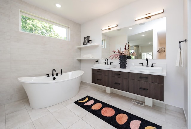 989 65th St, West Des Moines, IA 50266 - bathroom featuring double vanity, a soaking tub, tile walls, and tile patterned floors