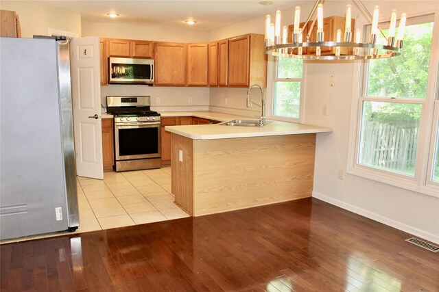 4015 Marigold Dr, Ames, IA 50014 - kitchen featuring appliances with stainless steel finishes, a chandelier, a peninsula, light wood-style flooring, and light countertops