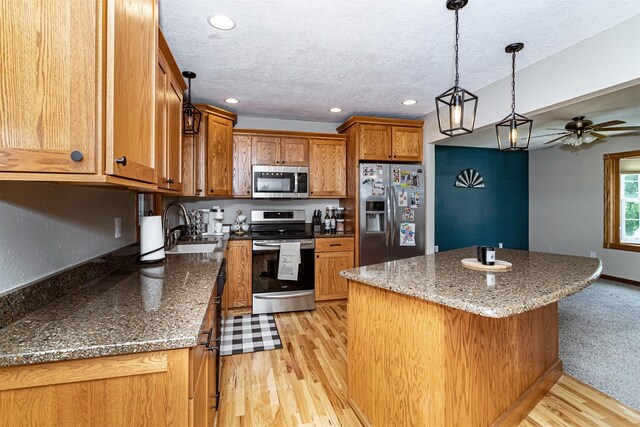 503 E 5th St, Huxley, IA 50124 - kitchen with appliances with stainless steel finishes, recessed lighting, brown cabinets, a textured ceiling, and a kitchen island