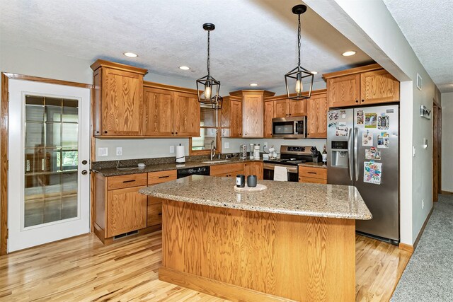 503 E 5th St, Huxley, IA 50124 - kitchen featuring stainless steel appliances, a textured ceiling, light wood finished floors, brown cabinetry, and a center island