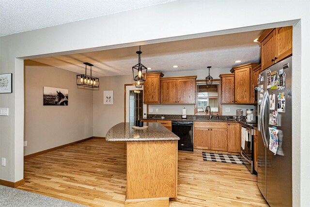 503 E 5th St, Huxley, IA 50124 - kitchen featuring stainless steel appliances, light wood-style flooring, a center island, pendant lighting, and brown cabinets