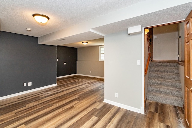 503 E 5th St, Huxley, IA 50124 - below grade area with wood finished floors, a textured ceiling, and stairway