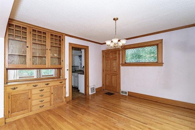 317 N Russell Ave, Ames, IA 50010 - unfurnished dining area featuring a chandelier, light wood-type flooring, a textured ceiling, crown molding, and healthy amount of natural light