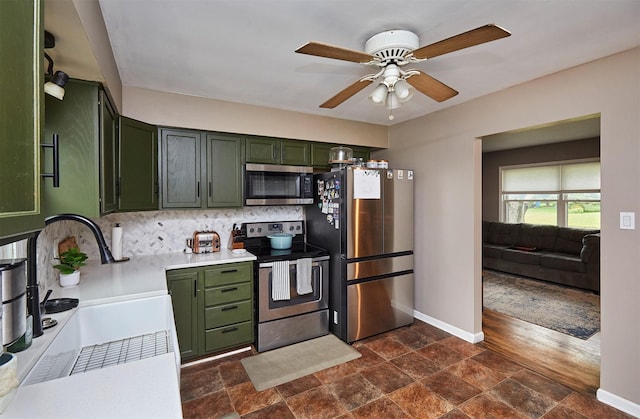 3925 55th St, Des Moines, IA 50310 - kitchen featuring green cabinets, stainless steel appliances, stone tile flooring, and decorative backsplash