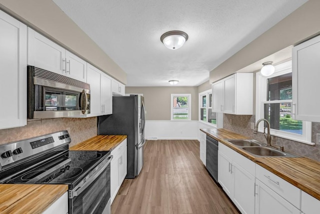 1516 73rd St, Windsor Heights, IA 50324 - kitchen featuring stainless steel appliances, wooden counters, light wood-style flooring, backsplash, and a textured ceiling