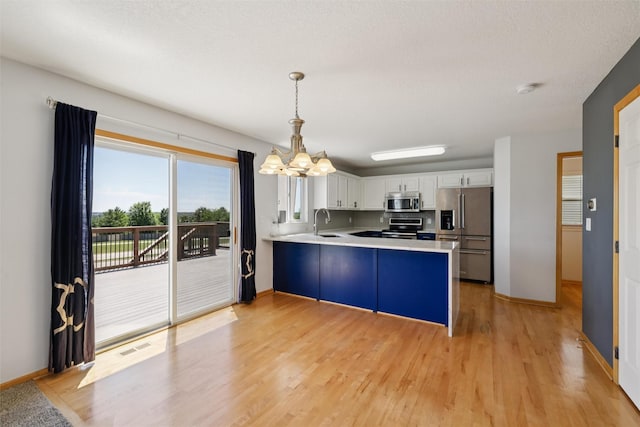 7039 Carey Ct, Johnston, IA 50131 - kitchen with appliances with stainless steel finishes, a peninsula, a chandelier, light wood-style flooring, and light countertops