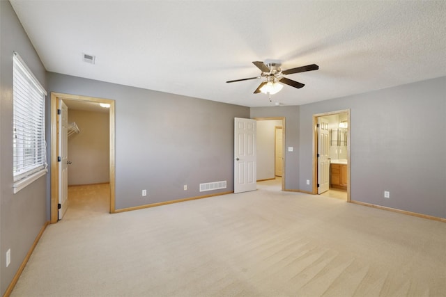 7039 Carey Ct, Johnston, IA 50131 - unfurnished bedroom with light carpet, a spacious closet, ensuite bath, and a ceiling fan
