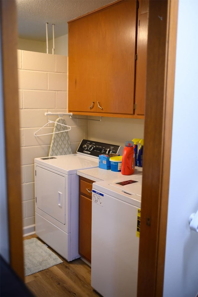 205 E 23rd St N, Newton, IA 50208 - washroom featuring washing machine and clothes dryer, cabinet space, wood finished floors, a textured ceiling, and concrete block wall