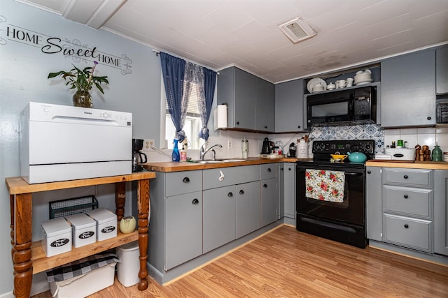 2003 Carroll St, Boone, IA 50036 - kitchen with black appliances, gray cabinetry, butcher block counters, decorative backsplash, and light wood-type flooring