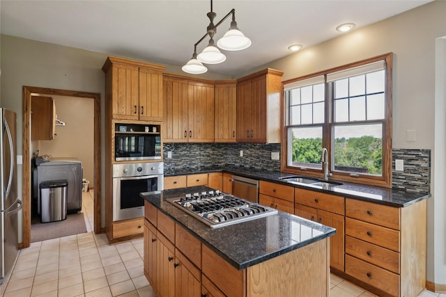 940 High Ave, Newton, IA 50208 - kitchen featuring appliances with stainless steel finishes, washing machine and clothes dryer, light tile patterned floors, a kitchen island, and decorative backsplash
