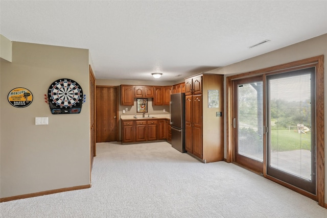 940 High Ave, Newton, IA 50208 - kitchen with freestanding refrigerator, light colored carpet, brown cabinets, and light countertops