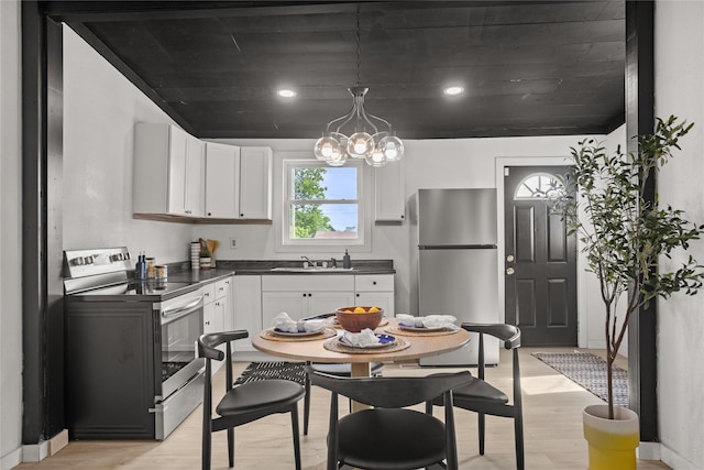 707 Bromley St, Marshalltown, IA 50158 - kitchen with appliances with stainless steel finishes, dark countertops, light wood-style floors, white cabinetry, and a chandelier