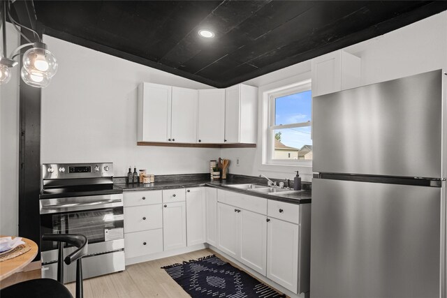 707 Bromley St, Marshalltown, IA 50158 - kitchen featuring stainless steel appliances, dark countertops, white cabinets, light wood-style floors, and recessed lighting